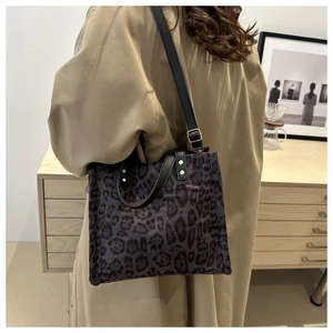 Close-up of leopard print tote bag with black leather straps and gold metal buckles