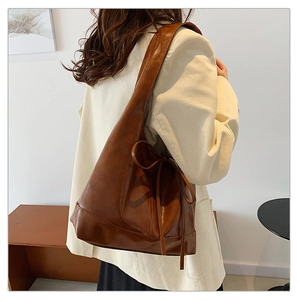 Detail of brown faux leather hobo bag side featuring a decorative bow on the shoulder strap
