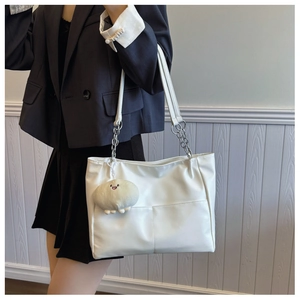 Detailed shot of white leather tote bag with silver chain strap and plush ball charm