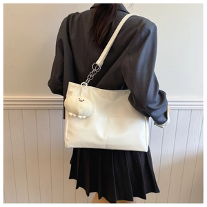 Detail of white PU leather tote bag with stylish plush cloud pendant on dark blazer