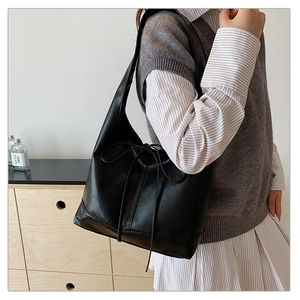 Detail of black faux leather tote with decorative bow and premium textured finish