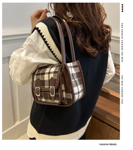 Detail view of the autumn plaid underarm bag with decorative leather straps and buckles