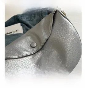 Detailed view of pink butterfly embroidery on silver-grey textured leather saddle bag