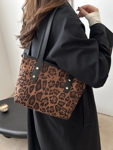 Borsa tote leopardata vintage con manici neri e borchie dorate indossata da una modella