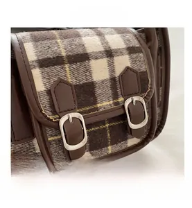 Close-up of vintage brown plaid fabric and leather straps with silver metal buckles