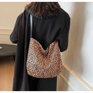Vue détaillée du sac à bandoulière imprimé léopard porté avec un manteau noir élégant