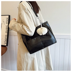 Detail of black large capacity tote bag featuring elegant stitching and plush charm