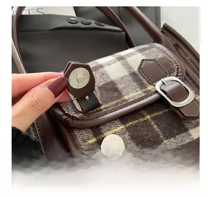 Detail of magnetic metal clasp on vintage striped crossbody bag with checkered fabric