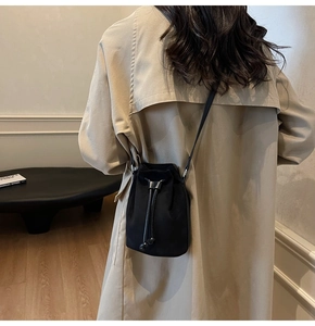 Modella che indossa una borsa a secchiello vintage in pelle scamosciata nera con tracolla