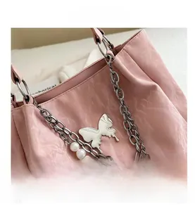 Detail view of pink textured tote with silver chain, pearls and butterfly charm