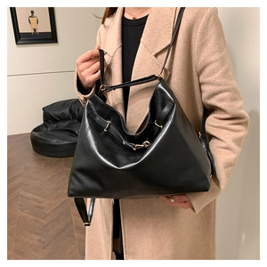 Detail of black leather tote bag featuring gold hardware and adjustable side straps