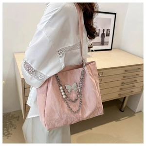 Detail of pink tote bag showing silver butterfly charm and white pearl chain decoration