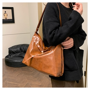 Detail of vintage brown tote bag showing glossy leather texture and metal buckles