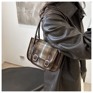 Detailed side view of the retro plaid underarm bag worn with a leather jacket