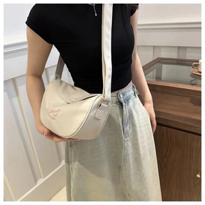Detail of off-white crescent crossbody bag featuring delicate pink butterfly embroidery