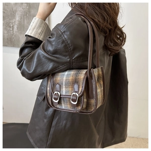 Detail view of vintage plaid pattern and leather trim on a retro crossbody bag