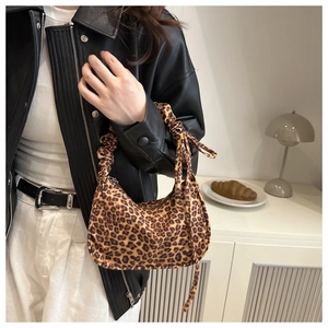 Detail of leopard print crescent bag featuring a pleated handle and side ribbon bow