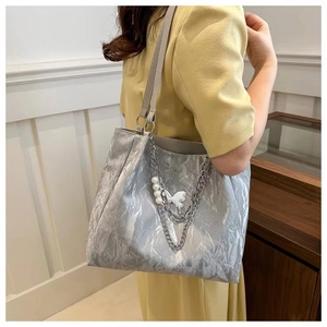 Silver metallic wrinkled tote bag with pearl and butterfly charms shown on model