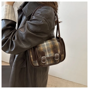 Detail view of vintage plaid wool underarm bag with leather trim and metal buckles