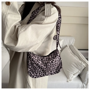 Detail of trendy leopard print shoulder bag with silver zipper closure on beige coat