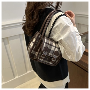 Detail of vintage plaid shoulder bag with brown leather trim and silver metal buckles