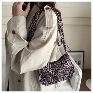 Detailed close-up of a leopard print shoulder bag in purple and black tones on a beige coat