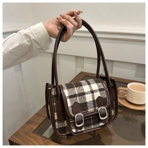 Close-up of retro plaid wool handbag with brown leather trim and silver metal buckles