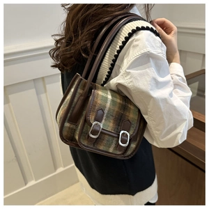 Detail of vintage plaid wool handbag with brown leather trim and silver metal buckles