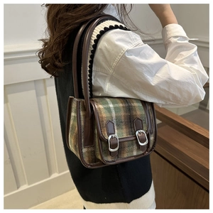Detail of vintage striped crossbody bag showing green-brown plaid texture and leather strap