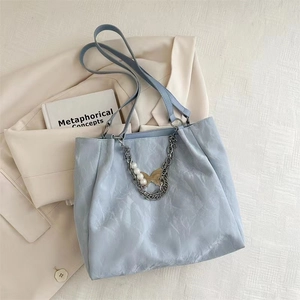 Detail of light blue tote bag featuring pleated texture, silver chain and pearl charms