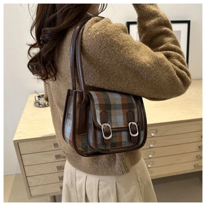 Detail view of vintage plaid shoulder bag with brown leather trim and silver buckles