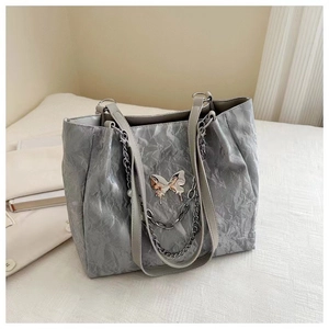 Detail of silver tote bag with metallic crinkle fabric and butterfly chain ornament
