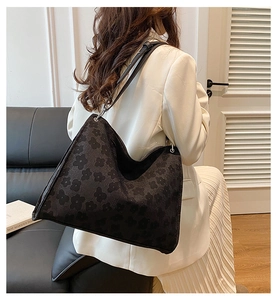 Détail du sac cabas en jacquard noir avec motif trèfle porté par un mannequin en blanc