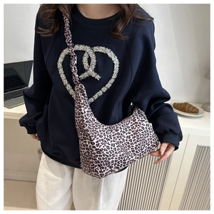 Detailed view of fashionable leopard print crescent shoulder bag on a female model
