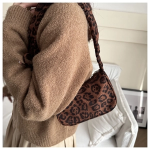 Vista modella della borsa a tracolla leopardata abbinata a un maglione marrone in casa