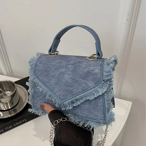 Close-up of blue denim envelope bag with frayed edges and silver chain strap details
