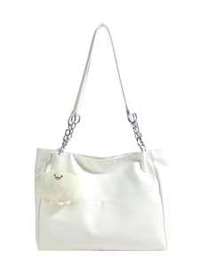 Minimalist white tote bag with silver chain straps and a plush smiley charm in front