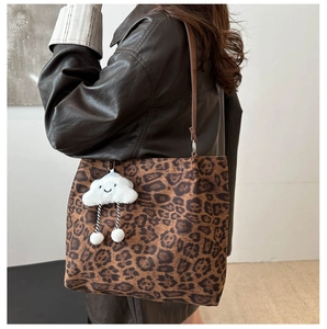 Detail of leopard print tote bag with brown leather strap and plush cloud charm
