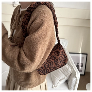 Dettaglio della borsa leopardata sottobraccio con tracolla a pieghe per moda autunno
