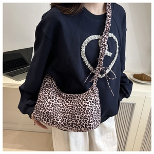 Close-up of leopard print canvas bag with wide shoulder strap and bow knot detail on model