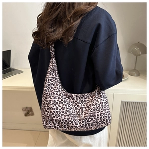 Detailed view of crescent leopard print tote bag styled on model with dark hoodie