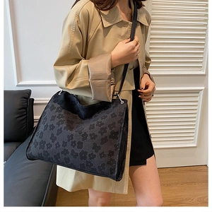 Détail d'un grand sac cabas en jacquard aux motifs floraux sombres porté à l'épaule