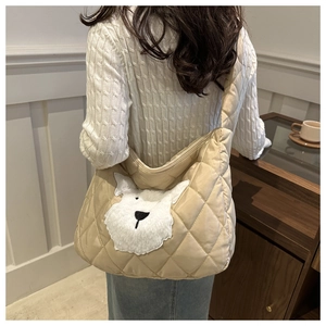Detail of a beige quilted shoulder bag featuring a cute plush dog patch decoration