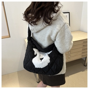 Detailed view of black quilted tote bag with white schnauzer plush patch on model back