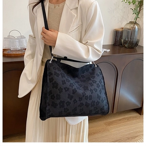 Gros plan sur un sac cabas noir à motif floral gris avec bandoulière dans un intérieur