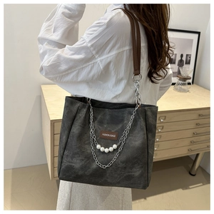 Detail of grey leather tote bag with silver chain and pearl decoration for casual style