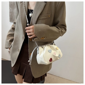Detail of cream white bucket bag with colorful heart patches and silver chain strap