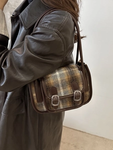Retro plaid wool shoulder bag with leather trim and silver buckles worn by a model