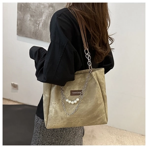 Detail of khaki tote bag with pearl chain decoration and leather logo patch on matte fabric