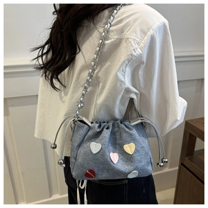 Detail of grey tweed bucket bag with colorful heart patches and silver chain strap
